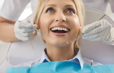 Doktor diş hekimi, klinik ziyareti sırasında dişçi teçhizatıyla hastanın ağız bakımını inceler, diş hekimliğinde kurtarma hizmeti sunar, profesyonel bir ortamda sağlığa odaklanır..