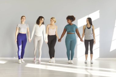 Spor giyim kuşamında spor giyinen neşeli kadın gruplarının spor salonunda arka arkaya durdukları uzun bir portre ya da forma eğitiminden sonra yoga stüdyosu. Spor sporu ve sağlıklı yaşam tarzı konsepti.