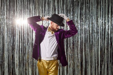 Mor takımlı mutlu dansçı, parlak gümüş bir arka planda disko partisinde müzik eşliğinde dans ediyor. Akşam kutlaması eğlence, eğlence ve canlı gece enerjisiyle doludur..