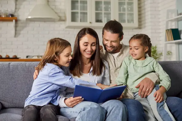 Kitap okuyan neşeli bir aile. Mutlu ebeveynler ve çocuklar ilginç bir hikayenin tadını çıkarıyorlar. Gülümseyen anne, baba ve çocuklar evlerindeki ya da evlerindeki kanepede oturup birlikte kitap okuyorlar.