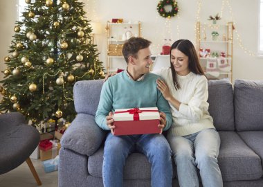 Olumlu adam, Noel ya da yeni yıl kutlaması sırasında bir kadının hediye kutusunu açıyor ve evdeki kanepede oturuyor. Aile, evli çift tatil sezonunun neşesini ve sıcaklığını paylaşıyor..