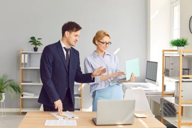 Ofiste çalışan insanlar. Dizüstü bilgisayar kullanan iki muhasebeci. Genç adam ve kadın iş arkadaşları birlikte bir ofis masasının başında dizüstü bilgisayarın ekranına bakıyorlar.