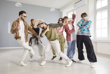 Modern dans stüdyosunda bir grup trend genç birlikte dans ediyor. Şık dansçılar hip hop hareketleri yapıyor, dans antrenmanında eğlenirken enerji ve yaratıcılıklarını ifade ediyorlar..