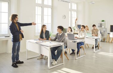 Okul dersi, erkek öğretmen genç üniversite arkadaşlarına soruyor, beyin fırtınası yapıyor üniversitede, üniversitede çalışma projesi yapıyor, birlikte öğreniyor, rapor veriyor, arkadaşça öğretiyor ve öğreniyor.