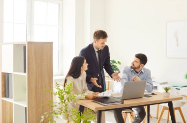 Bir ofis toplantısında birlikte çalışan iş arkadaşları, takım çalışması ve işbirliği içinde. İş stratejileri ve planlarıyla ilgili sohbet, profesyonel çevrede etkili iletişim.