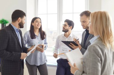 Olumlu iş adamları, ofis toplantısı veya konferans, güçlü takım iletişimi ve organizasyonu, grup işbirliği ve verimliliğini gösteren belgeleri ele alır ve sohbet ederler..