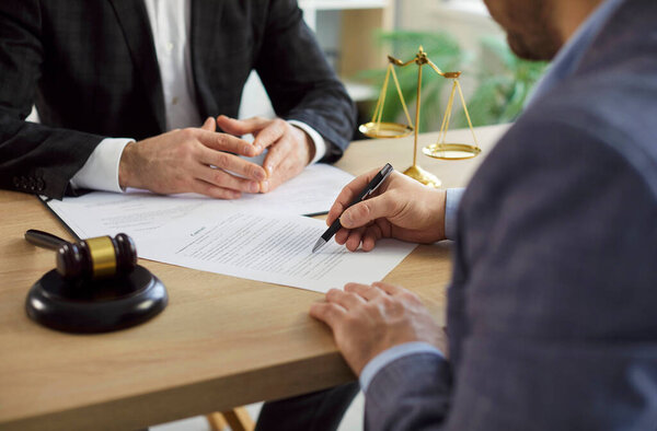 Клиент подписывает договор во время деловой встречи с адвокатом или адвокатом, фокусируясь на договоре и праве в профессиональной обстановке с чувством документации и юридического сотрудничества и поддержки.