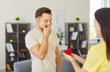 Mutlu kadın elinde yüzükle ona evlenme teklif ediyor, şaşırmış adam mücevherlere şokla bakıyor, evlilik teklifi yapıyor, birlikte özel bir anın tadını çıkarıyor. İlişki 