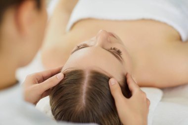 Kozmetik bilimci veya dermatolog, güzellik salonundaki kadın hastalara yüz masajı veya spa tedavisi sunar, profesyonel bir ortamda bakım ve dikkat ile cilt sağlığına odaklanır..