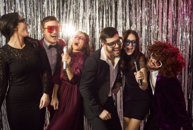 Karaoke eğlence klubü eğlencesi eğlence arkadaşları sevinç, tatilciler heyecanlanıyor, hareket ediyorlar, terfi ediyorlar başarıyı kutluyorlar, esprili bir adam, metalik, parlak, yağmurlu bir çelenk.