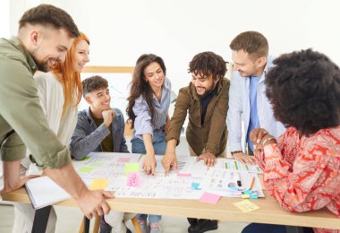 Ofisteki bir toplantıda bir grup iş adamı belgeler üzerinde birlikte çalışıyor. Takım, bir iş planı üzerinde çalışırken sohbet, planlama ve işbirliğine girişir..