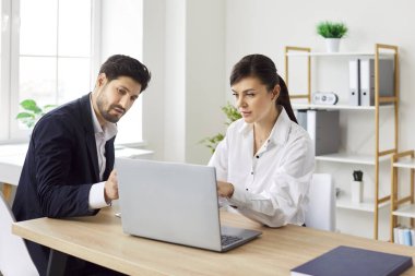 Genç, konsantre, ciddi iş adamları şirket çalışanları ofiste toplanıyor, masa başında oturuyor, dizüstü bilgisayar ekranlarına bakıyor ve finansal verileri analiz ediyorlar. Takım çalışması konsepti.