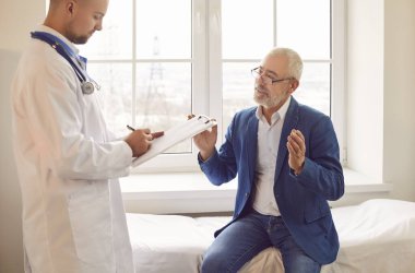 Üst düzey erkek hasta hastane muayenesi sırasında bir doktor ya da hemşireyle görüşüyor. Yaşlılara bakım ve tedavi, tıbbi danışma ve sağlık desteği.