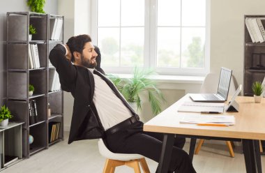 Rahatlamış iş adamı iş yerinde uzanmış, gözleri kapalı bir şekilde işten kaytarıyor. Resmi takım elbiseli genç, kendine güveni tam bir çalışan ofiste dizüstü bilgisayarla çalışıyor..