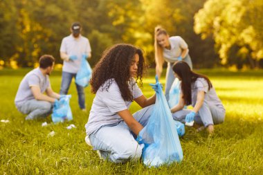 Odaklanmış gönüllü ekip temizlik sırasında şehir parkında çöp ve çöp topluyor, toplumu ve işbirliğini destekliyor, özel takım çalışması ve bakımıyla dolu kamusal alanda ekolojiyi geliştiriyor.