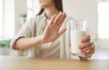 Bir bardak süt tutan ve laktoz alerjisi, evde beslenme düzenini ve gıda seçimlerini etkileyen bir alerji nedeniyle sağlık kısıtlamalarına odaklı kişisel bir ortamda süt vermeyi reddeden bir kadın..