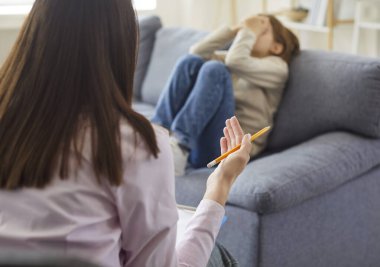 Terapi seansı sırasında psikologların ofisinde oturan küçük bir çocuğun portresi. Terapist, depresyondaki çocuğa korkuları ve stresiyle yardım etmeye çalışıyor..