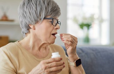 Kıdemli kadın evde sağlık hizmetleri için diyet, vitamin ya da tıbbi reçete gibi haplar alır ve tedavinin önemine dikkat ederek kişisel ortamdaki sağlığa odaklanır..