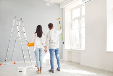 Açık renkli yeni duvarları tamir etmekten mutlu olan evli genç çift ilk eve taşınmaktan zevk alıyor, ev sahipleri, kiracılar, taşınma ve dikiz aynasından keyif alan erkek ve kadın çift.