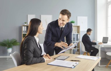 İş arkadaşları bir ofiste muhasebe üzerinde birlikte çalışıyor, toplantı sırasında bir tartışmaya giriyorlar. Takım çalışması işbirliği, mesleki sohbet ve ofis verimliliğini vurgular.