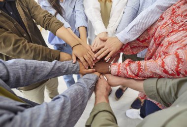 Çeşitli insanlardan oluşan bir ekip ellerini birleştiriyor. Bir grup çok ırklı erkek ve kadın el ele tutuşuyor. Takım çalışması, arkadaşlık, destek, topluluk, işbirliği kavramları