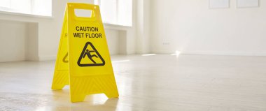 Boş bir odada ya da ofisinde yerde duran ıslak tabelalı sarı uyarı levhasını kapat. Temizlik, temizlik ve ev işi konsepti. Seçici odaklanma. Pankart.