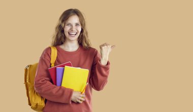 Sırt çantası ve bej arka planda fotokopi alanı gösteren dosyaları olan gülen öğrenci kız. Kırmızı kazaklı, dalgalı açık renk saçlı mutlu bir kadın. İnsani duygular, pazarlama, iyi teklif kavramı.