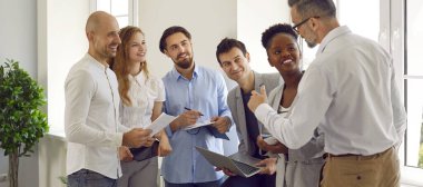 Mutlu iş adamları ağ oluşturma etkinliğinde konuşur, başlangıç fikirlerini paylaşır ve iş toplantısında yeni yenilikleri tartışırlar. Çok uluslu bir grup insan dikkatle işadamını dinliyor..