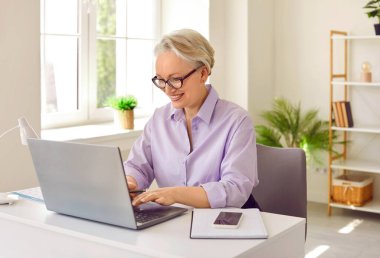 Olgun olgun yaşlı kadın öğretmen okul çocuklarını ve öğrencileri internetten internetten öğreniyor online sohbetlerde soruları cevaplıyor ve eğitim almasına uzaktan yardım ediyor.