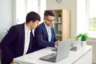 Finans şirketinin ofisindeki dizüstü bilgisayarlarda çift olarak çalışan iki erkek arkadaş. Takım elbiseli konsantre genç adamlar masada oturup iş projelerini ve mali raporları tartışıyorlar..