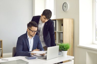 Şirket ofisinde çalışan meşgul insanlar. Erkek şirket çalışanları evrak işleriyle uğraşıyor. İki genç adam birlikte bazı önemli iş belgelerini inceliyor.