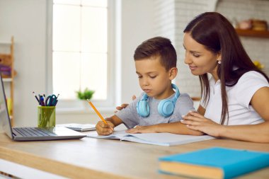 Evde eğitim gören küçük sevimli çocuk resim yapmayı öğreniyor. Evde bakım yapan anne ya da bebek bakıcısı konsantre kreş çocuğu el yazısı öğretiyor. Çocuklu bir kadın dizüstü bilgisayarın önünde oturuyor..