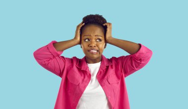 Hata yapan ya da bir şeyi unutan komik bir kadın açık mavi arka planda kafasını tutuyor. Yüzünde suçlu ifadesi olan Afro-Amerikalı bir kadının portresi. Web pankartı.