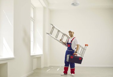 Mutlu teknisyen işe yüksek katlama merdiven ve alet çantasıyla geldi. Video izleme, izleme, havalandırma, aydınlatma sistemleri kurma kavramı. Tadilattan sonra boş ofis.