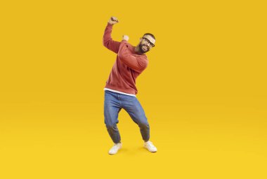 Neşeli, neşeli ve kaygısız adam stüdyoda turuncu arka planda dans ederek eğleniyor. Yakışıklı ve şık beyaz sakallı adam ellerini sallayarak dans ederken günlük kıyafetlerle dans ediyor. Tam uzunluk.