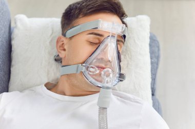 Tıbbi yüz maskesi takan erkek hasta oksijen maskesi, ciğerler için oksijen gazı solumak, havalandırma ve sağlık hizmetleri yetişkin desteği, koronavirüs hastalığından kaynaklanan yapay akciğer havalandırması, korona virüsü zatürresi.