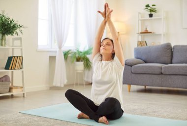 Yoga nilüferinde kıdemli kadın evde poz veriyor, temel pozları öğreniyor, nefes alma teknikleri öğreniyor, farkındalık pratiği yapıyor, sportif yaşlılar oturuyor, zihin çalışıyor, vücut meditasyonu yapıyor, yaşam dengesini geliştirmek için fitness dersleri alıyor.