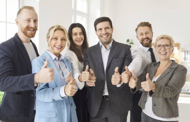 İş adamlarının grup portresi. Başparmak gösteriyorlar ya da ofiste jestler yapıyorlar. Takım çalışması, işbirliği ve başarı, profesyonel bir ortamda onay ve pozitif enerjiyi sembolize ediyor.