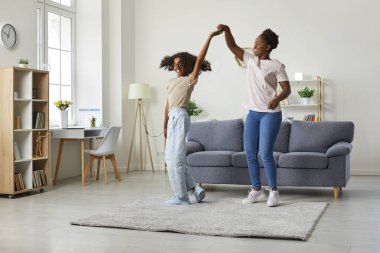 Anne ve kızı boş vakit geçiriyor. Koyu tenli genç kızı ile genç Afrikalı Amerikalı kadın hafta sonu evde eğlenirken dans ediyor. Aile, nesil ve insan kavramı.