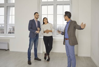 Genç ve mutlu bir çifte güzel bir ev gösteren bir emlakçı. Profesyonel emlakçı parlak yeni bir daire gösterdi. Başarılı bir aile ev sahibi olmaya hazır. Emlak piyasası kavramı.