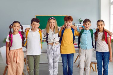 Bir grup ilkokul öğrencisi sıraya girip birbirlerine sarılıyorlar. Mutlu arkadaşlarının portresi, sınıf arkadaşlarının günlük giysiler giyip kameraya bakmaları. Okul eğitimi kavramı