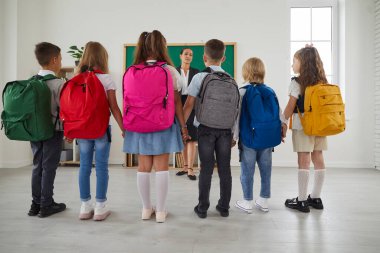 Sınıf arkadaşları dersten önce ya da ilk okul gününde sınıf öğretmeninin etrafında dikilip neden bahsettiğini dinliyorlar. Eğitim, ilkokul ve okul konseptine dönüş.