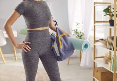 Spor çantasında spor aletleri ya da aksesuarları olan bir kadının karın kaslarının yakın çekimi. Sporcu spor salonuna hazırlanıyor, atletik figürlerini sergiliyor ve sağlık, spor ve eğitime odaklanıyor..