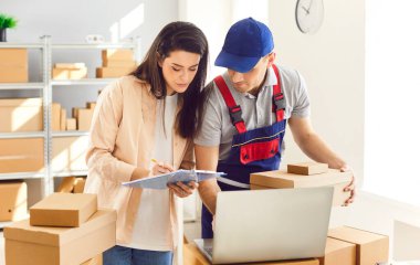 Depoda lojistik ya da dağıtım merkezindeki kadın küçük işletme sahibiyle çalışan teslimat işçisi bir müşterinin siparişini hazırlıyor. Stok envanteri.