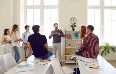 Erkek profesör sınıfta öğrencilerle gayri resmi bir konuşma yapıyor. Erkek ve bayan öğrenciler öğretmenlerinden bazı açıklamalar istiyorlar. Üniversitede veya üniversitede eğitim