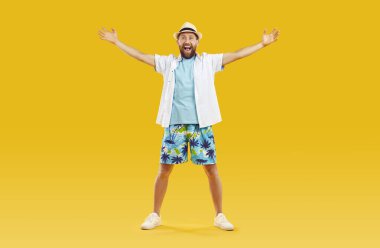 Plaj kıyafetleri içinde kollarını açmış neşeli komik adam seni yazlık otelde gördüğüne sevindi. Şortlu, tişörtlü, tişörtlü ve panamalı neşeli adamın portresi turuncu arka planda eğleniyor..