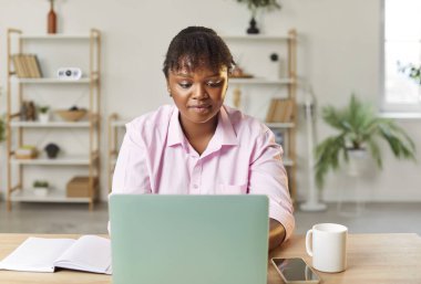 İş yerinde, iş yerinde, iş yerinde dizüstü bilgisayarıyla çalışan ve monitörlere bakan Afro-Amerikalı bir iş kadınının portresi..