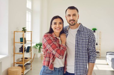 Oturma odasında duran mutlu bir çiftin aile portresi. İçten gülümsemelerle, mutluluğu yayarlar, birlikte olmanın mutluluğunu somutlaştırırlar..