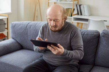 Evde elinde tablet bilgisayar, telefon ekranı, internet bağlantısı sorunu olan kafası karışmış yaşlı bir adam üzgün hissediyor. Yeni bir uygulama, cihaz çalışması öğreniyor. 