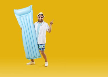 Şişme yüzme yatağı turuncu arka plandaki fotokopi alanını gösteren neşeli bir adam. Güneş gözlüklü ve plaj elbiseli neşeli beyaz adam gülümseyerek yaz ürününün reklamını yapıyor. Pankart.